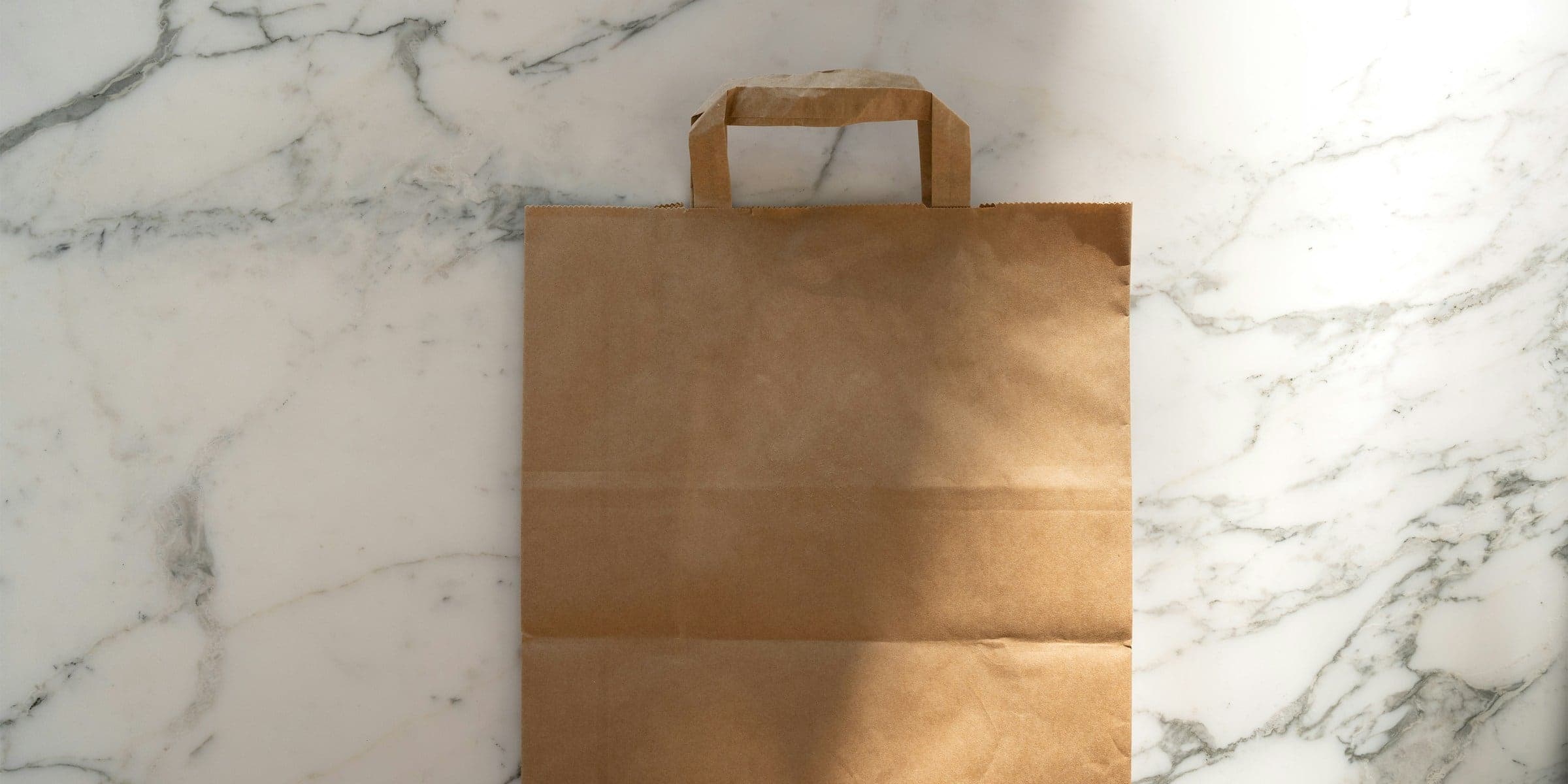 A plain kraft paper shopping bag on a marble counter