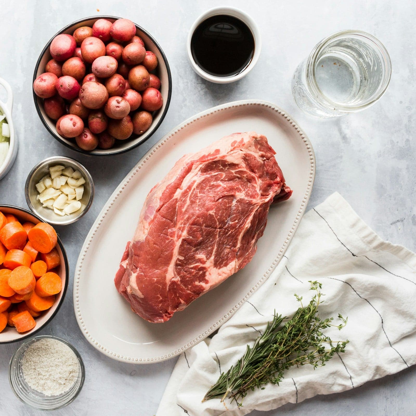 Ingredients for one recipe laid out from above: a cut of beef, potatoes, carrots and thyme
