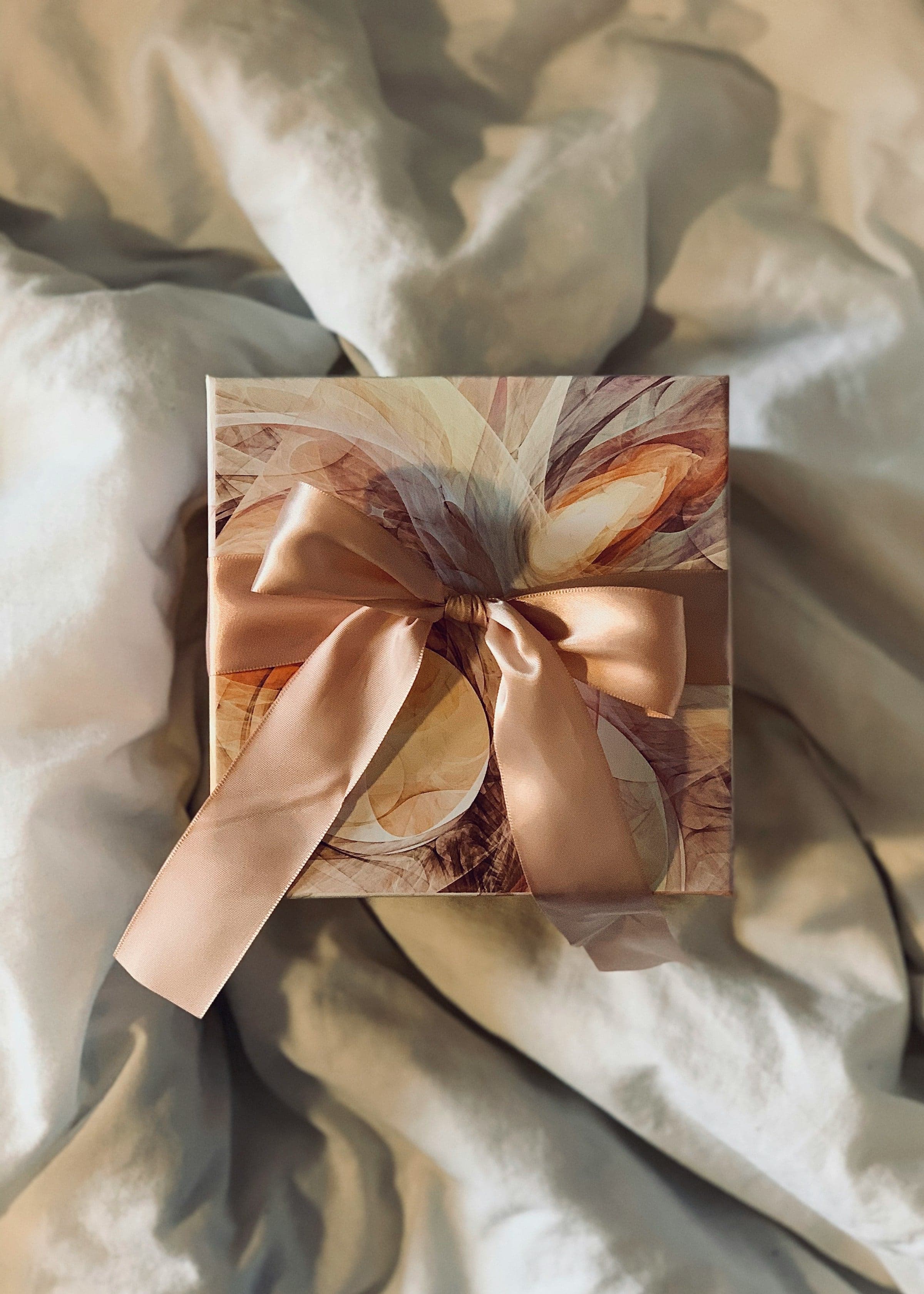 A gift wrapped in marbled paper with a satin bow